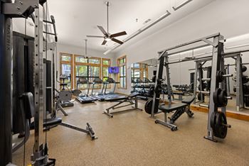 A spacious gym with a variety of equipment and a ceiling fan.
